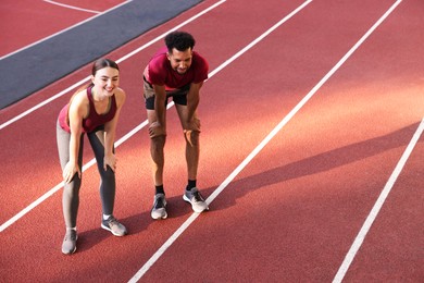Photo of Sporty couple resting after run at stadium. Space for text