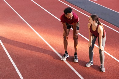 Photo of Smiling couple resting after run at stadium. Space for text