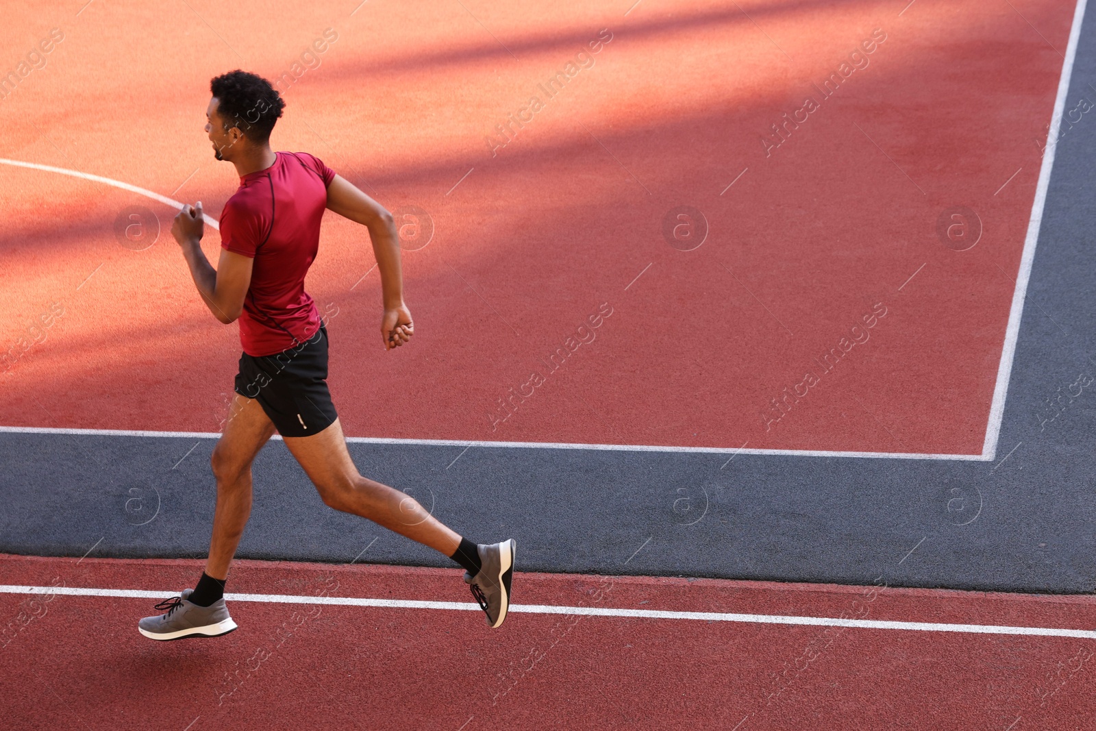 Photo of Handsome man in sportswear running at stadium. Space for text