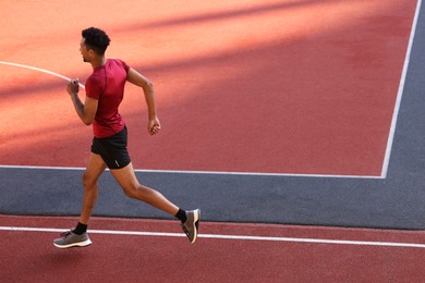 Photo of Handsome man in sportswear running at stadium. Space for text