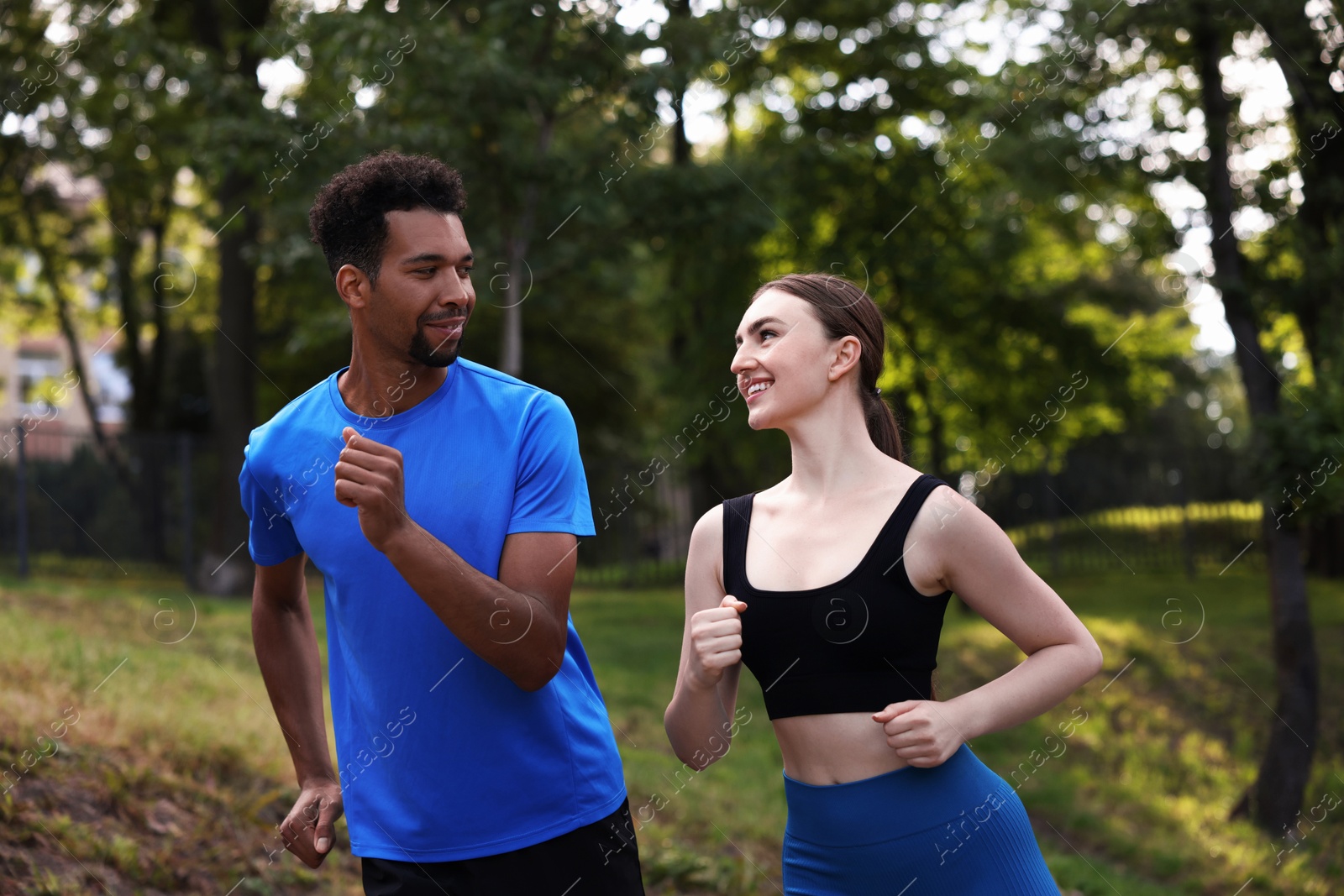 Photo of Smiling couple in sportswear running in park