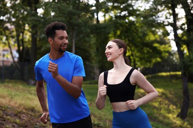 Photo of Smiling couple in sportswear running in park