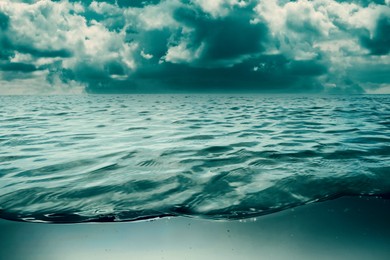 Image of Sea water surface and underwater view. Cloudy sky above
