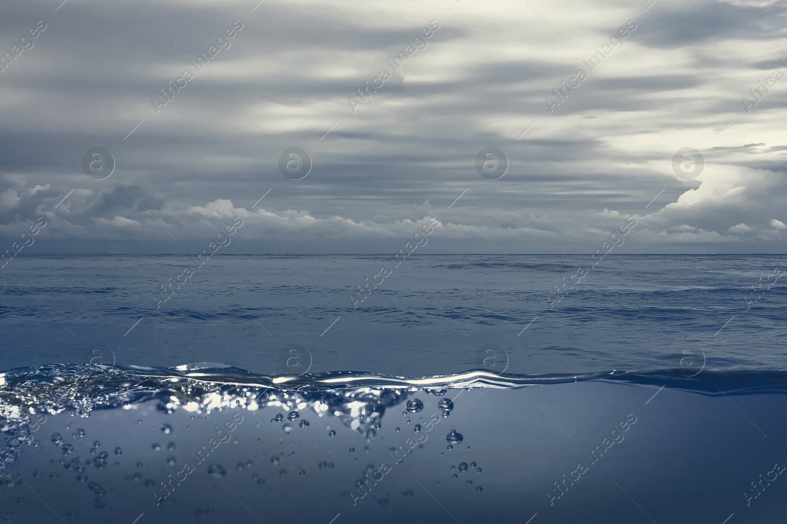 Image of Sea water surface and underwater view. Cloudy sky above