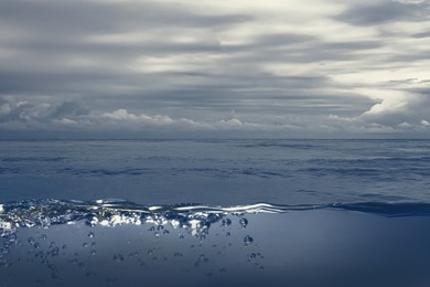 Image of Sea water surface and underwater view. Cloudy sky above