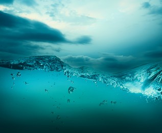 Image of Sea water surface and underwater view. Cloudy sky above
