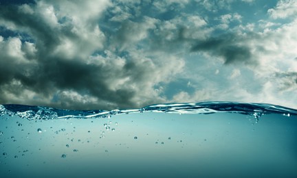 Image of Sea water surface and underwater view. Sky with clouds above