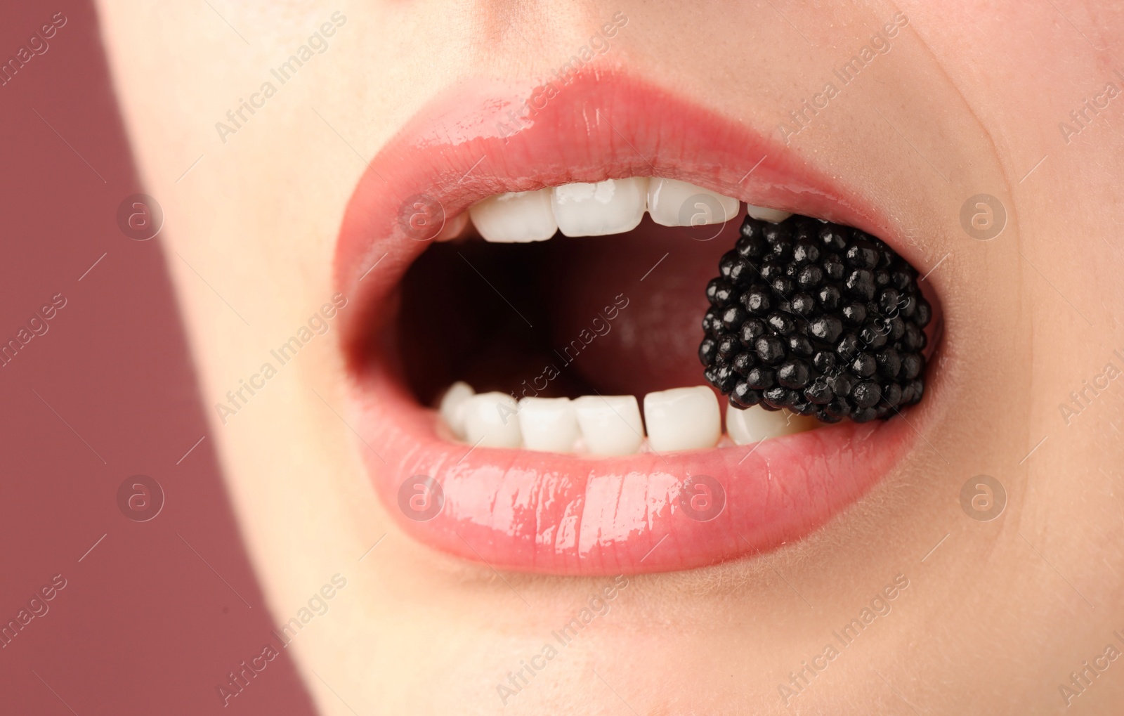 Woman with beautiful lips makeup and blackberry on dusty pink background, closeup Photo of Woman with beautiful lips makeup and blackberry on dusty pink background, closeup