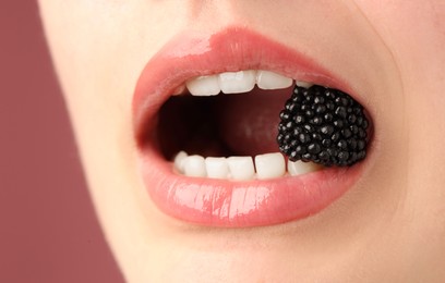 Photo of Woman with beautiful lips makeup and blackberry on dusty pink background, closeup