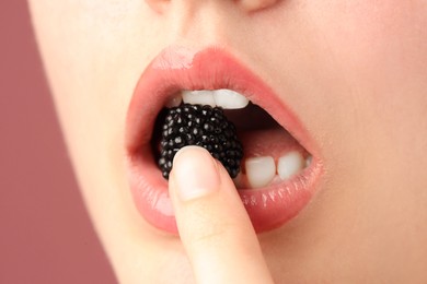 Photo of Woman with beautiful lips makeup and blackberry on dusty pink background, closeup