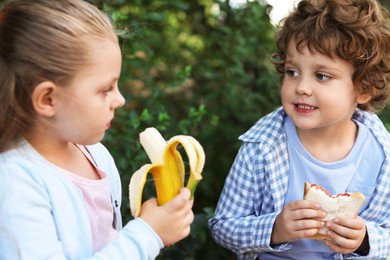 Photo of Cute kids eating food outdoors. School lunch