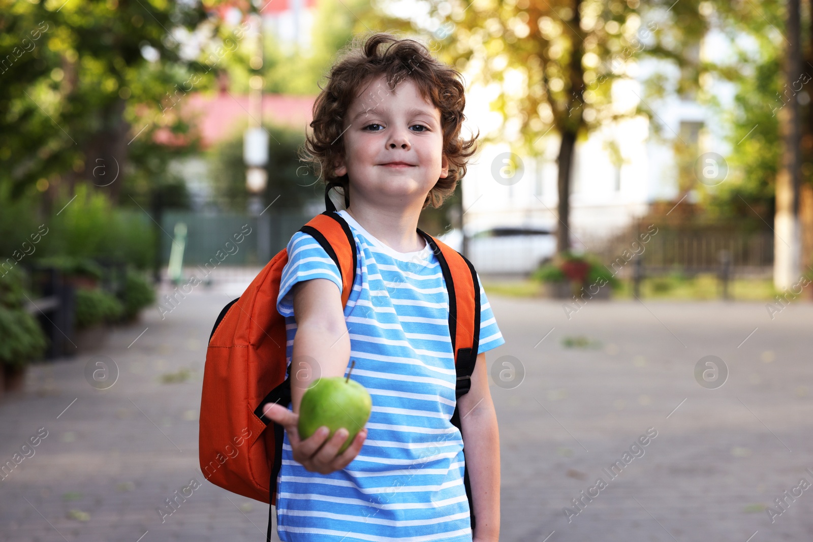 Photo of Cute little boy with apple outdoors. School lunch