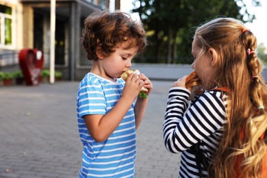 Photo of Cute kids eating sandwiches outdoors. School lunch