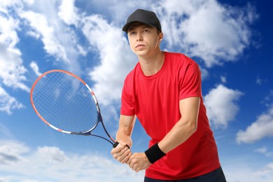Image of Man playing tennis against blue sky with clouds