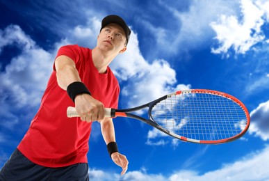 Image of Man playing tennis against blue sky with clouds, low angle view