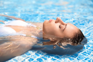 Photo of Beautiful young woman relaxing in outdoor swimming pool