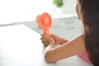 Photo of Little girl with portable fan at home, closeup. Summer heat
