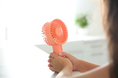 Photo of Little girl with portable fan at home, closeup. Summer heat