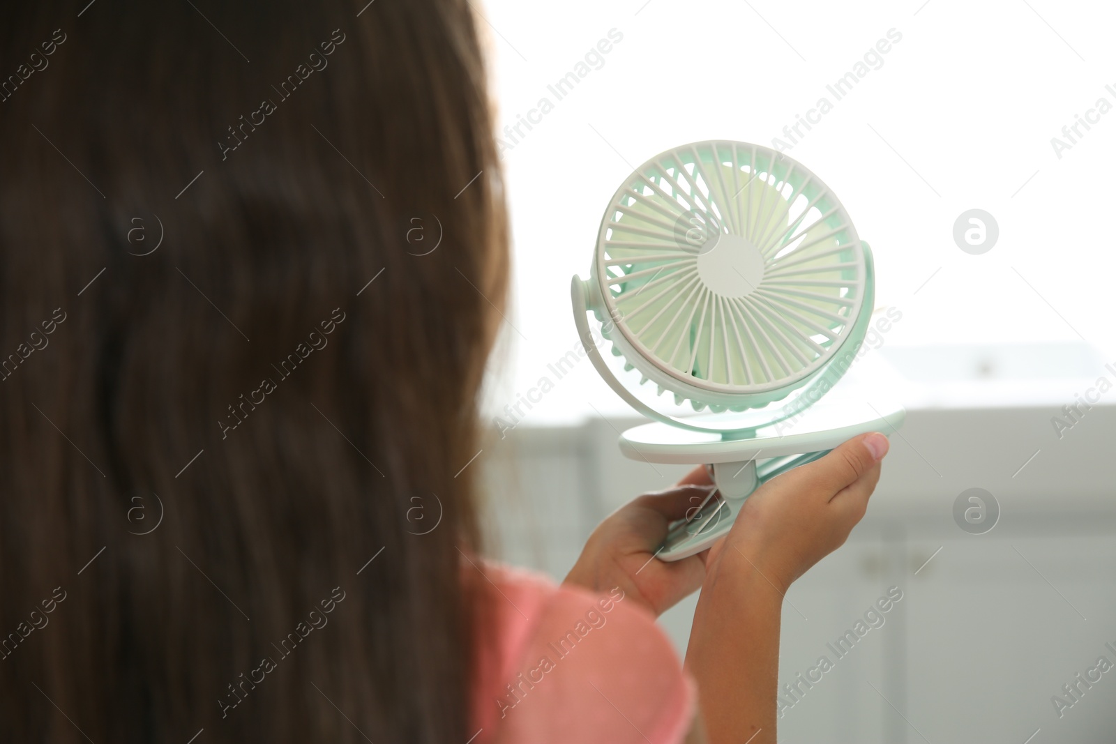 Little girl with portable fan at home, closeup. Summer heat Photo of Little girl with portable fan at home, closeup. Summer heat