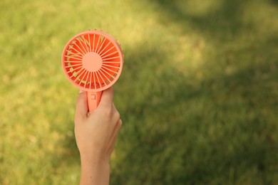 Photo of Woman holding portable fan outdoors on sunny summer day, closeup. Space for text