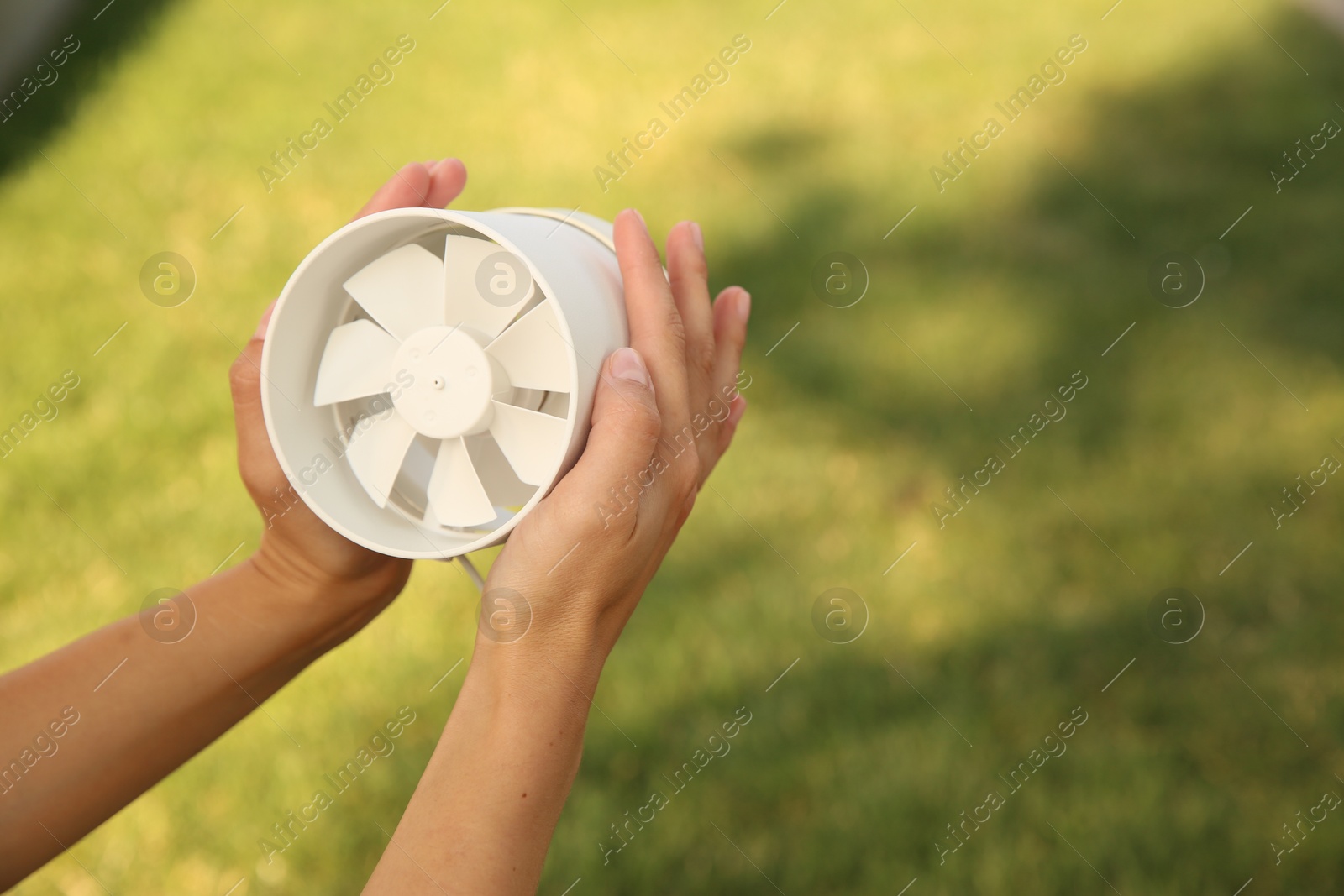 Photo of Woman holding portable fan outdoors on sunny summer day, closeup. Space for text