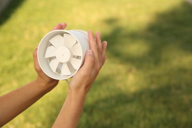 Photo of Woman holding portable fan outdoors on sunny summer day, closeup. Space for text