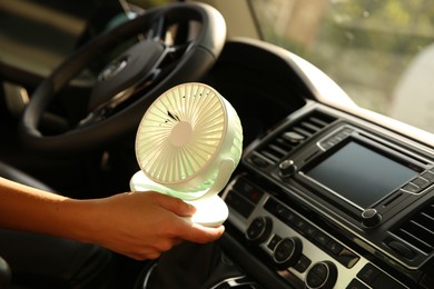 Photo of Woman with portable fan in car on hot summer day, closeup