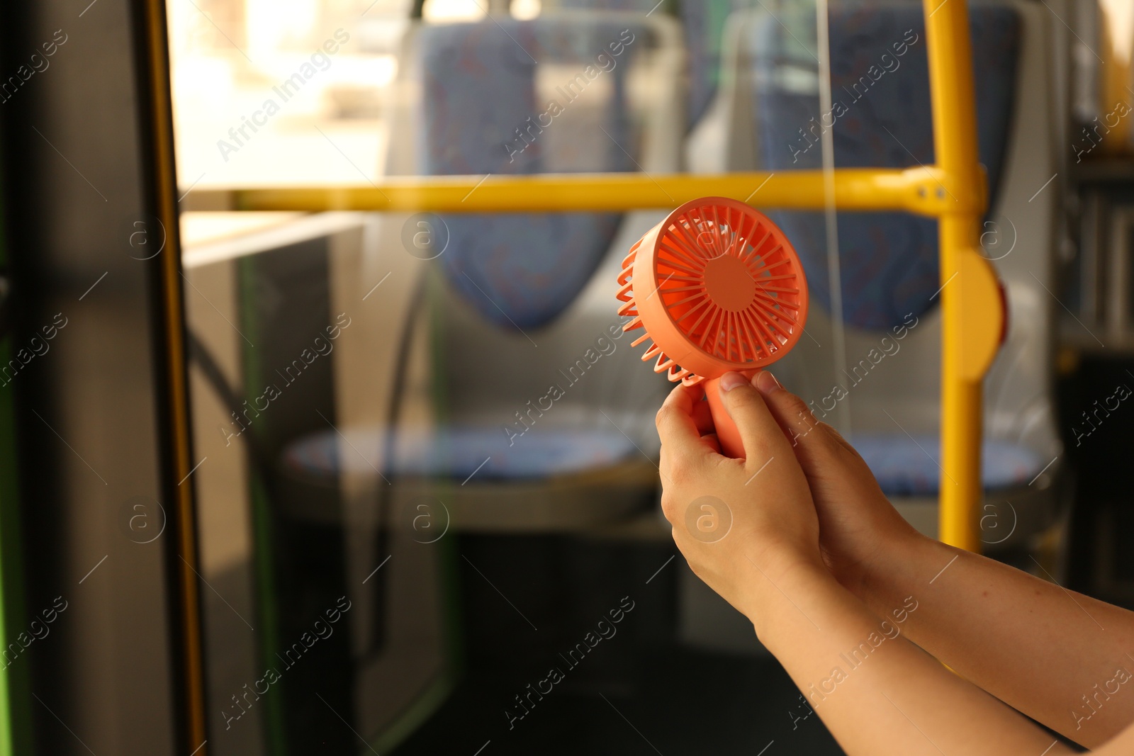Woman with portable fan in bus, closeup. Summer heat Photo of Woman with portable fan in bus, closeup. Summer heat