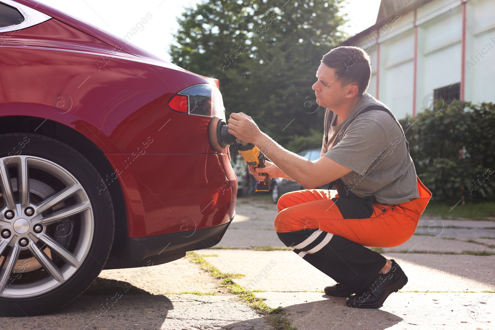 Photo of Man polishing car with orbital polisher outdoors