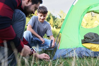 Photo of Father and son setting up camping tent outdoors, closeup