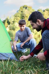 Photo of Father and son setting up camping tent outdoors