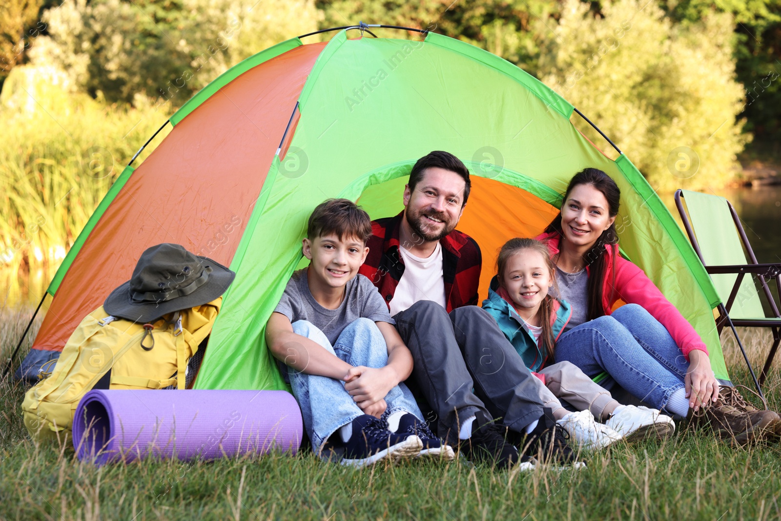 Photo of Happy family spending time together with camping tent and tourist equipment outdoors