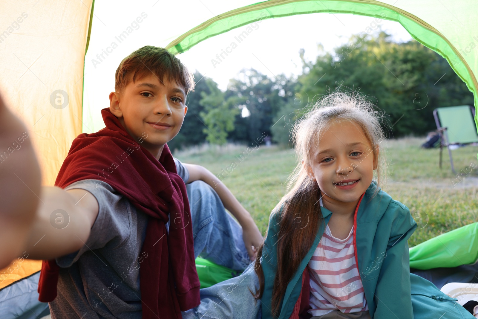 Happy brother and sister taking selfie in camping tent outdoors Photo of Happy brother and sister taking selfie in camping tent outdoors