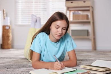 Photo of Teenage girl studying with books on floor at home