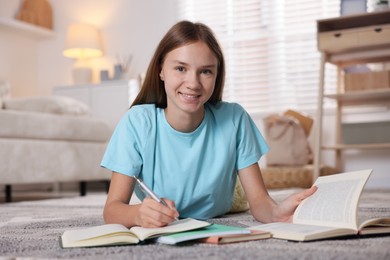 Photo of Teenage girl studying with books on floor in room. Homeschooling