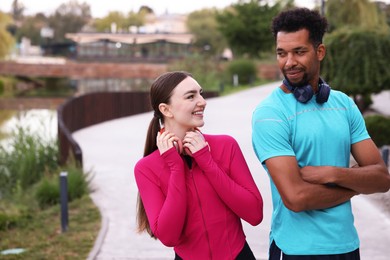 Photo of Smiling runners with headphones outdoors. Space for text