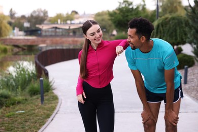 Photo of Smiling runners resting outdoors. Space for text