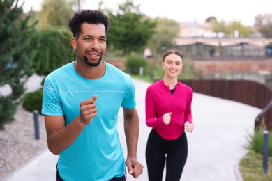 Photo of Happy couple in sportswear running outdoors. Healthy lifestyle