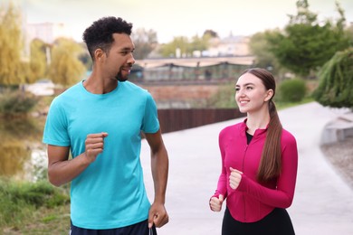 Photo of Happy couple in sportswear running outdoors. Healthy lifestyle