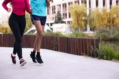 Photo of Couple in sportswear running outdoors, closeup. Space for text
