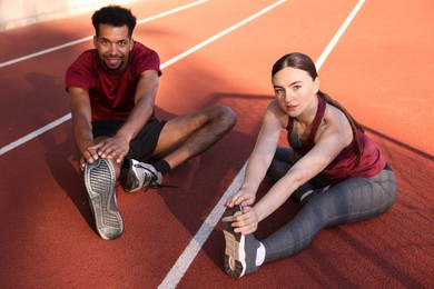 Photo of Couple in sportswear stretching before run at stadium