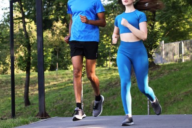 Photo of Couple in sportswear running in park, closeup