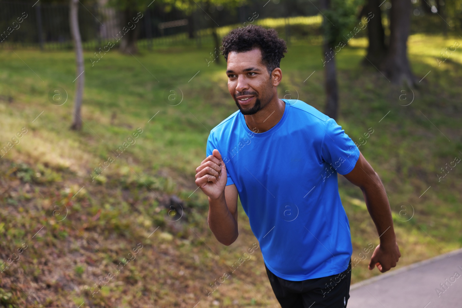 Photo of Smiling man running in park. Space for text