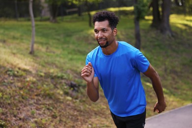 Photo of Smiling man running in park. Space for text