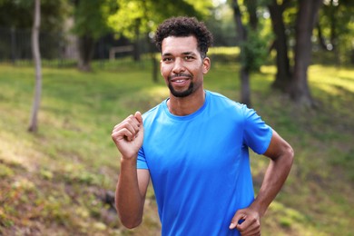 Photo of Portrait of smiling man running in park