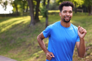 Photo of Smiling man running in park. Space for text