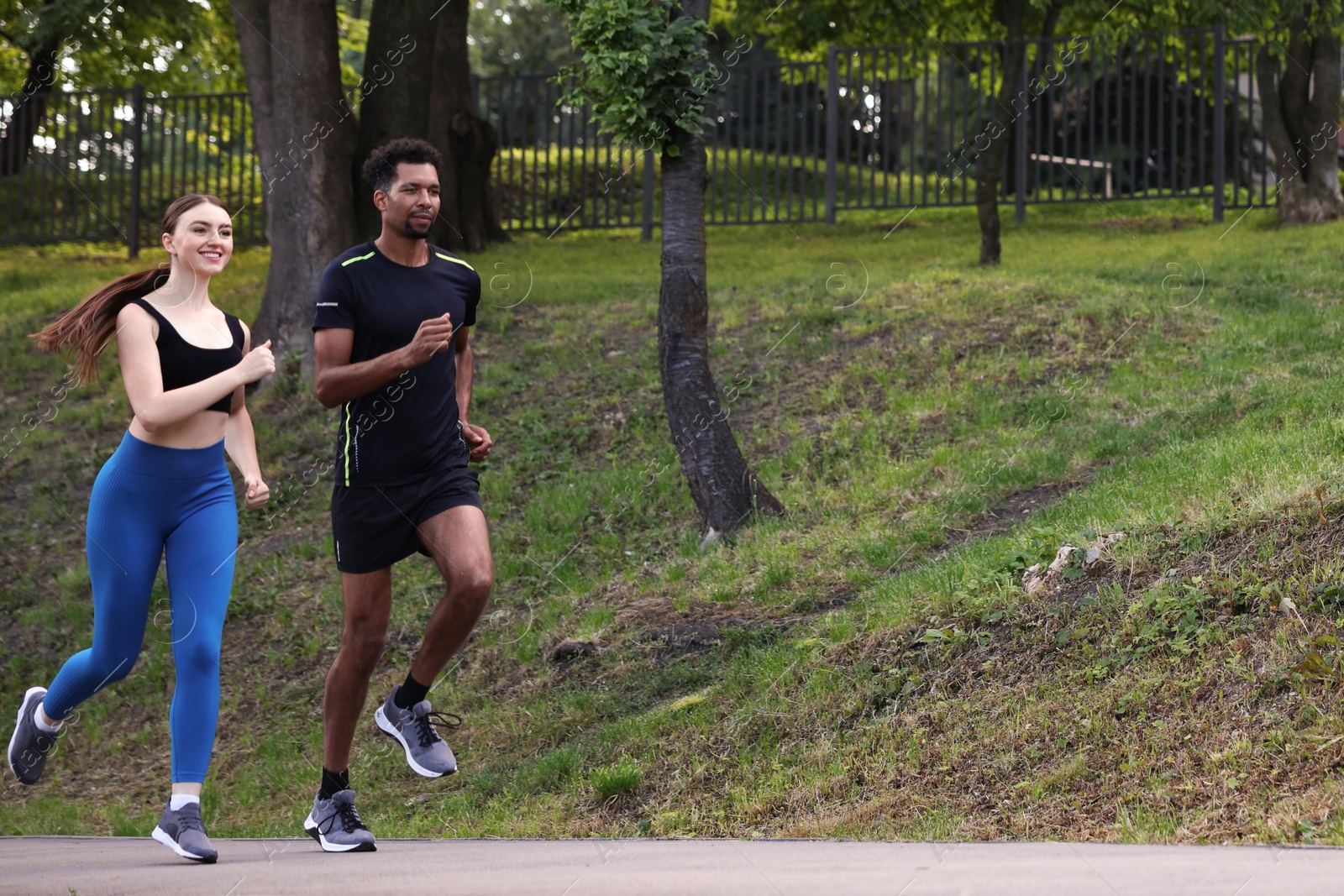 Couple in sportswear running in park, low angle view. Space for text Photo of Couple in sportswear running in park, low angle view. Space for text