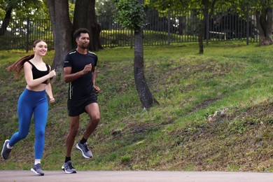 Photo of Couple in sportswear running in park, low angle view. Space for text