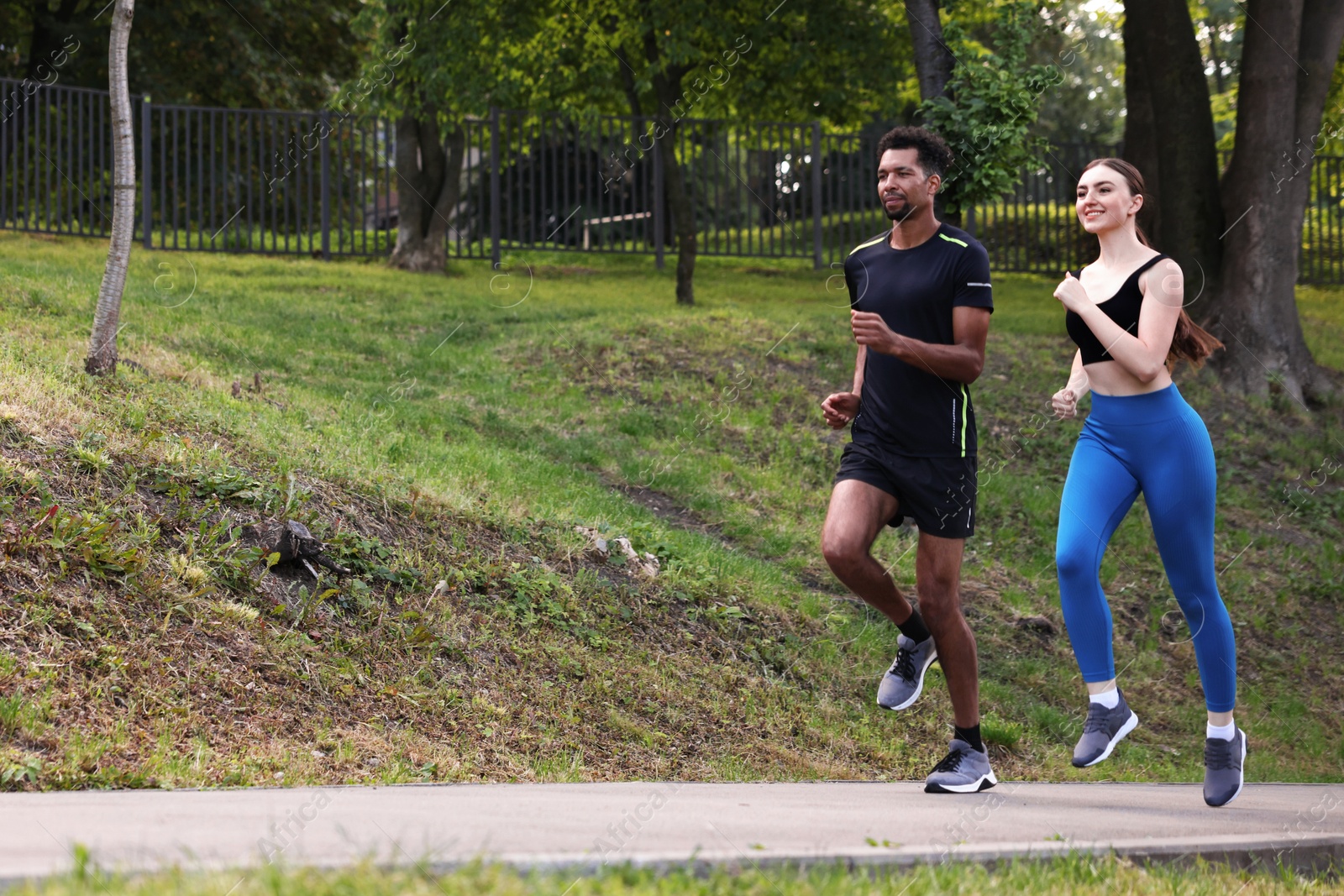 Couple in sportswear running in park, low angle view. Space for text Photo of Couple in sportswear running in park, low angle view. Space for text