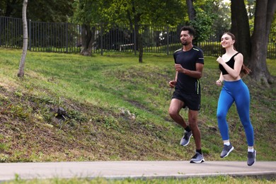 Photo of Couple in sportswear running in park, low angle view. Space for text